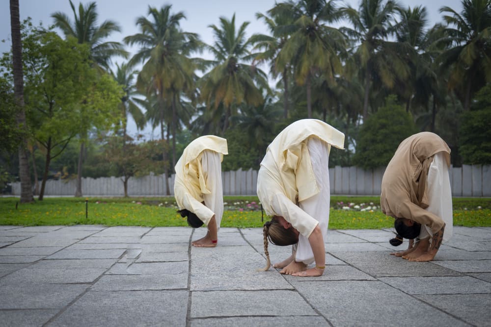 Une flexion avant debout, trois pratiquants